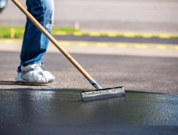A worker from Legacy Paving carefully adds sealant to a driveway, showing attention and skill in asphalt repair. A worker from Legacy Paving carefully adds sealant to a driveway, showing attention and skill in asphalt repair.
