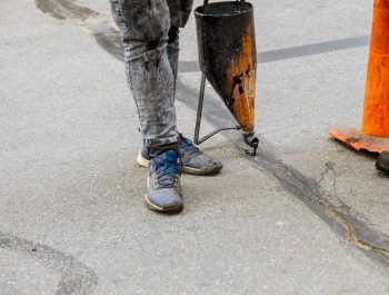 Someone from Legacy Paving carefully repairs a crack in an asphalt surface, showing the skill needed for professional paving work. Someone from Legacy Paving carefully repairs a crack in an asphalt surface, showing the skill needed for professional paving work.